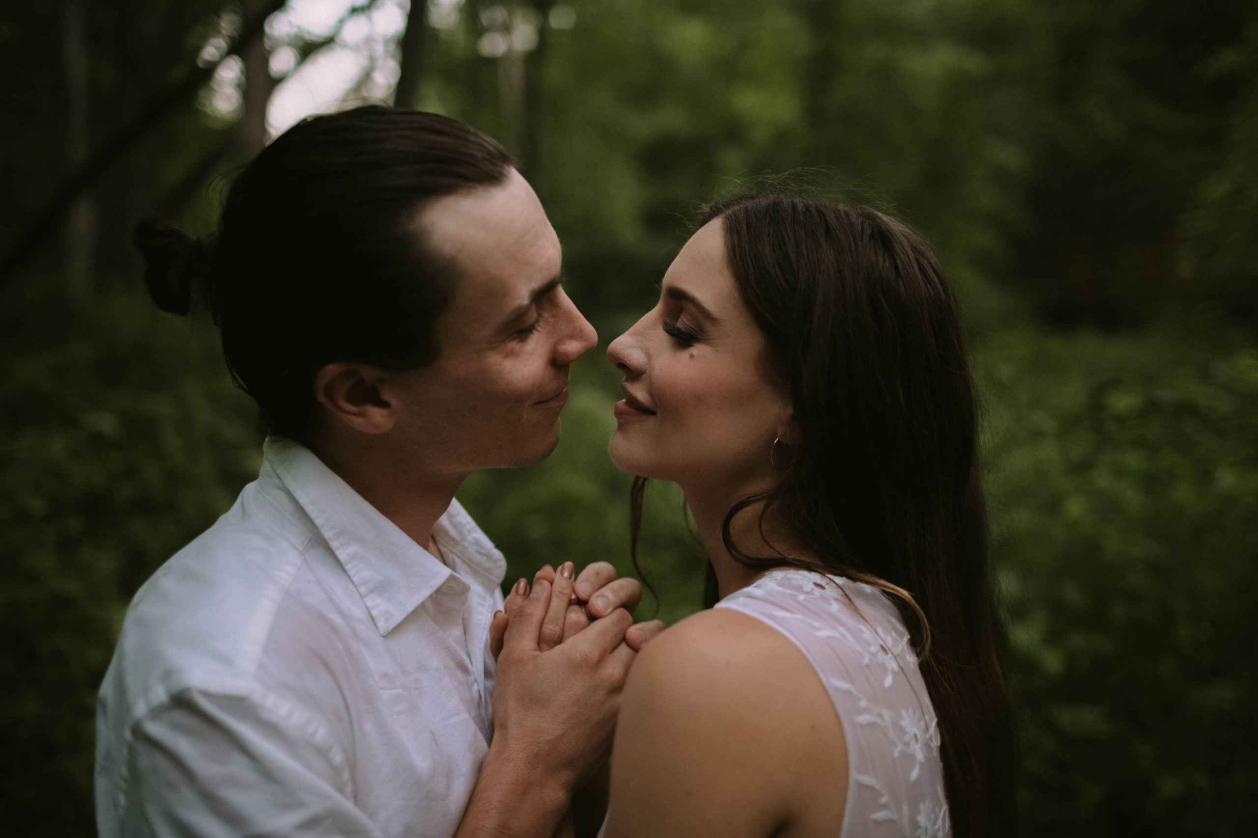 Couple comes nose-to-nose in the woods.