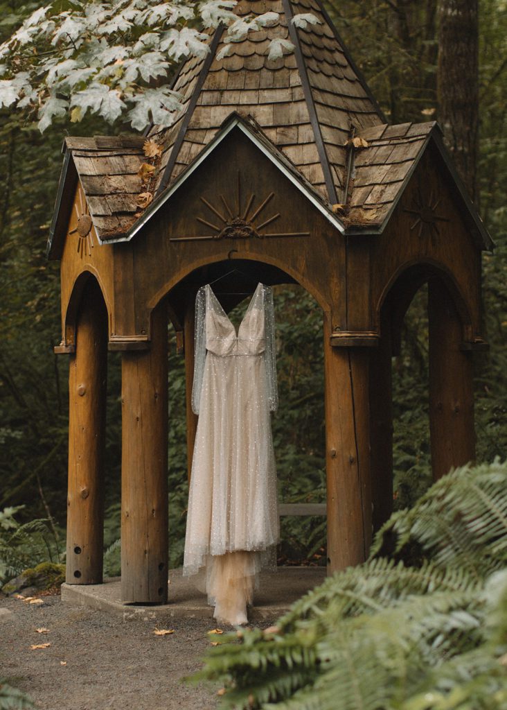 Wedding dress hangs on unique wood structure.