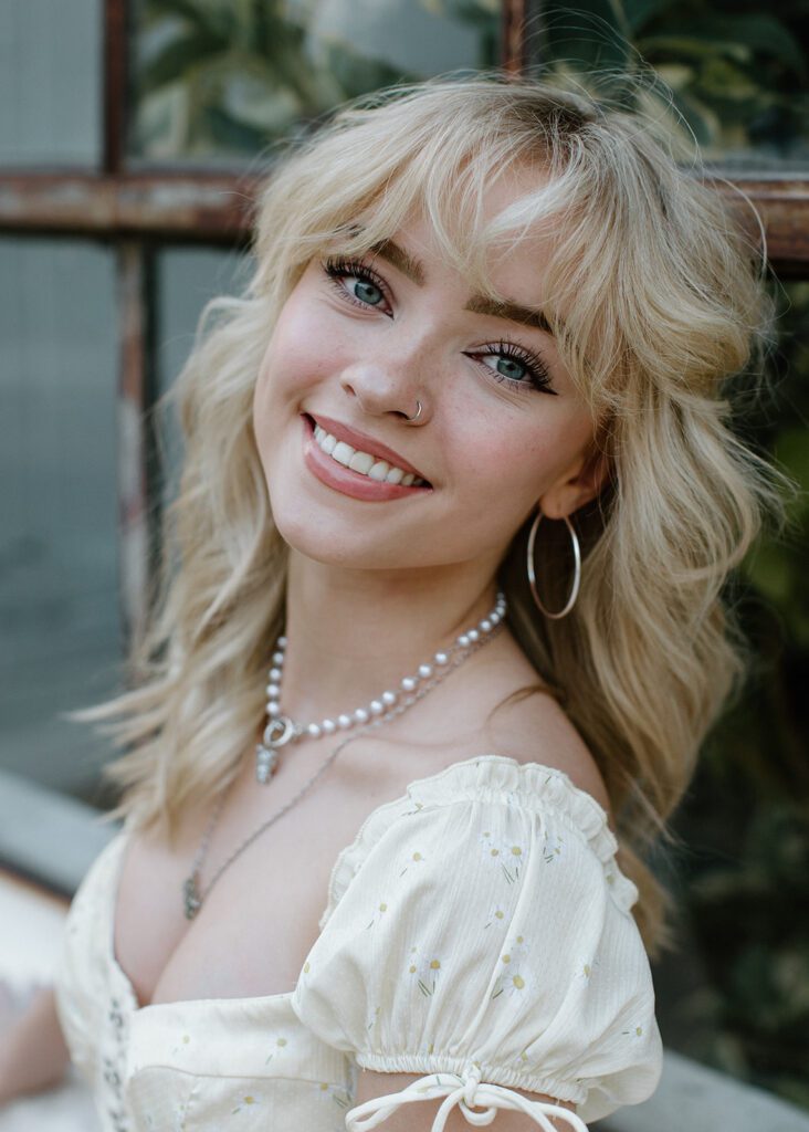 Subject poses by window at Northeast Mpls Senior Session