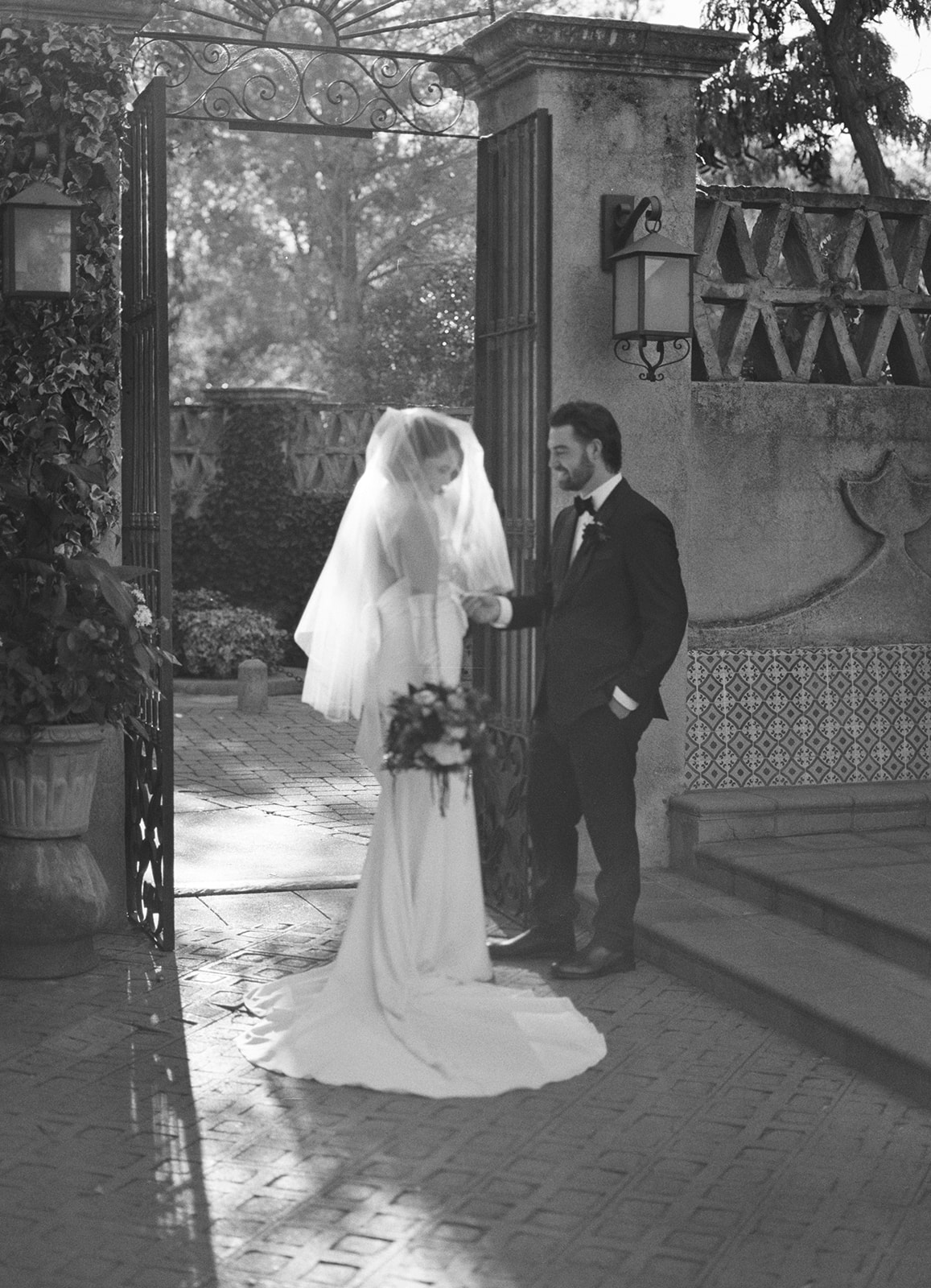 Bride and groom backlit by sun in a brick square.