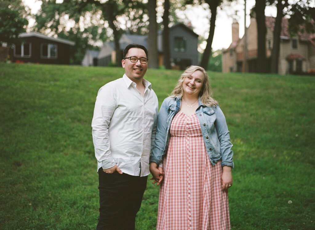 Couple laughs into the camera, at neighborhood engagement session.