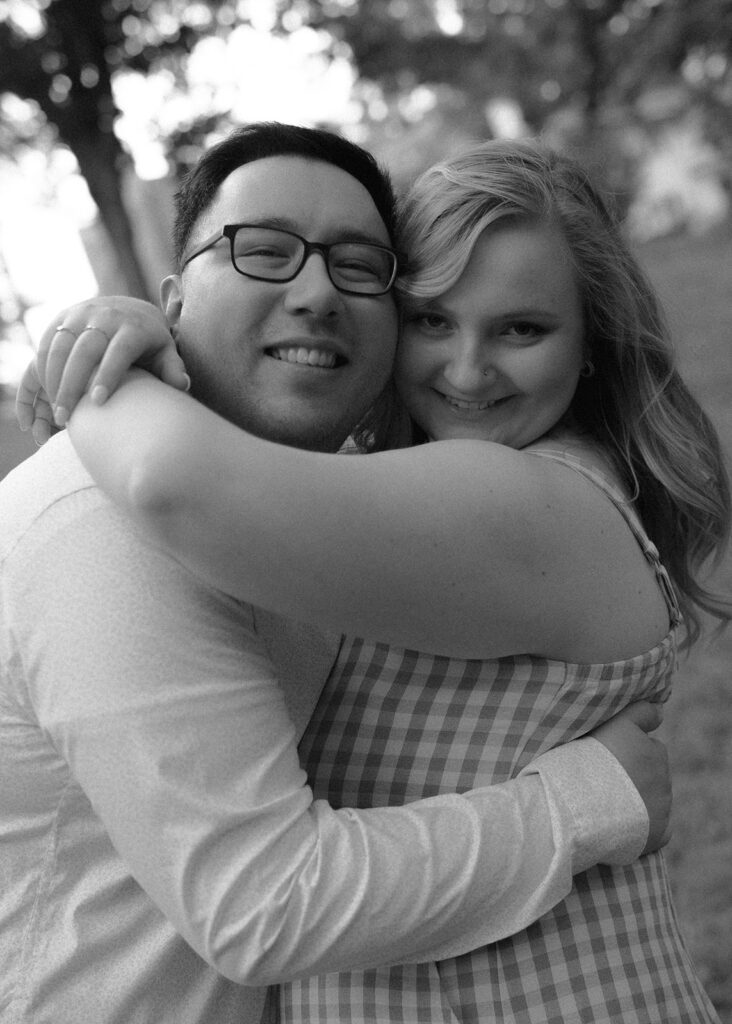 Couple smiles at the camera, at neighborhood engagement session.