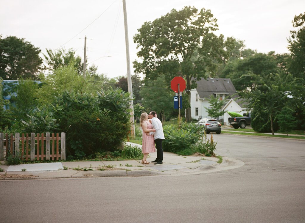 Couple kisses on street corner at neighborhood engagement session.